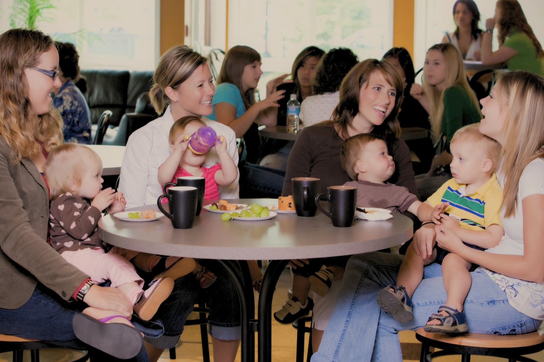 Mums and babies gathered around a cafe table at a brunch session